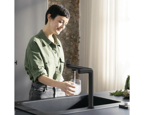 Frau füllt ein Glas Wasserhahn in einer modernen Küche.