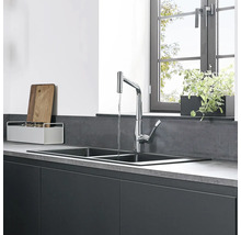 Küchenspüle mit Wasserhahn und Küchenutensilien vor Fenster