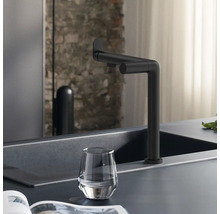Schwarzer Wasserhahn an einer Spüle mit einem Glas Wasser.