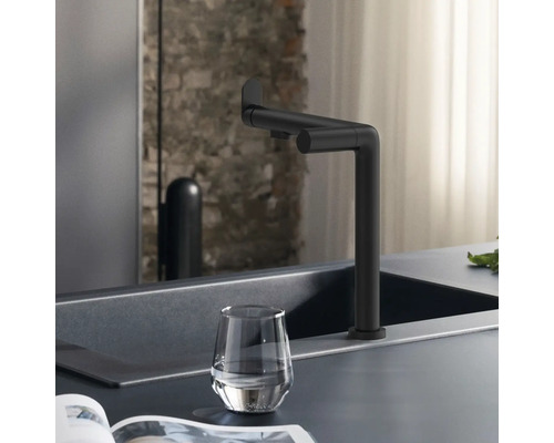 Schwarzer Wasserhahn an einer Spüle mit einem Glas Wasser.