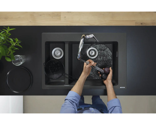 Aufnahme einer Doppelspüle mit Wasserhahn und Person, die Pflaumen wäscht