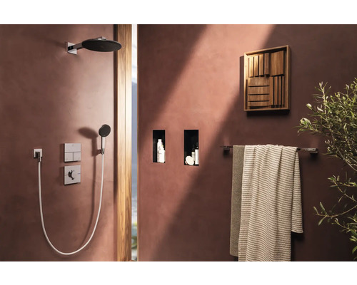 Duschbereich mit Kopfbrause, Handbrause, Ablagen, Handtüchern und Wanddekoration in einem Badezimmer.