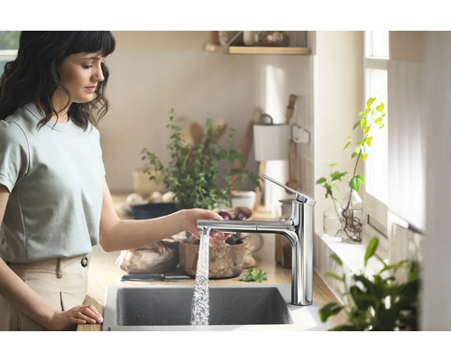 Frau bedient Küchenarmatur aus Chrom in heller Küche