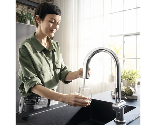 Frau füllt Glas mit Wasserhahn über Spüle