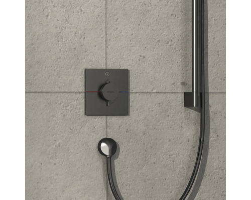 Brausethermostat mit Handbrause an einer grauen gefliesten Wand