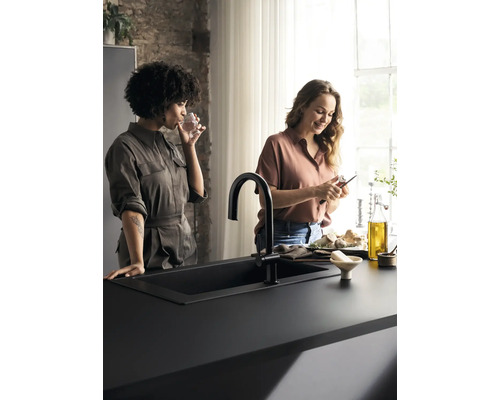 Schwarzes Spülbecken mit zwei Frauen in einer Küche.