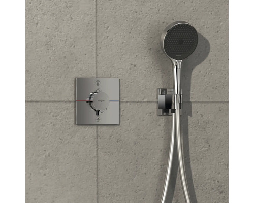 Aufputz-Thermostat mit Handbrause vor einer grauen Wand.