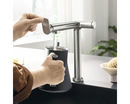 Wasserhahn aus Edelstahl mit Person, die Wasser in einen Behälter einfüllt