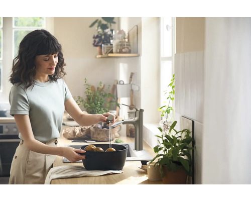 Frau wäscht Kartoffeln in der Küchenspüle mit Küchenarmatur.