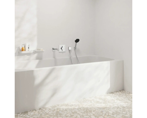 Badezimmer mit Badewanne, Armatur und Ablageflächen für Badutensilien.