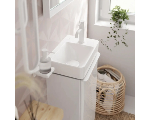 Badezimmerwaschtisch mit Armatur, Seifenspender und Aufbewahrungskorb.