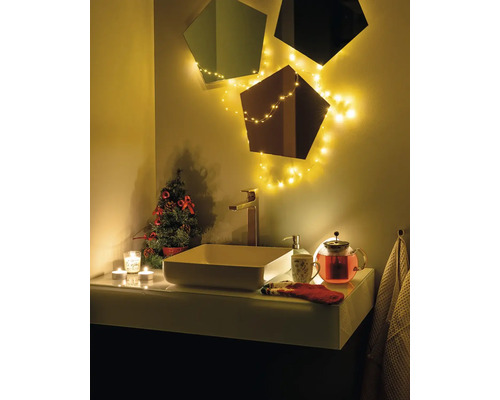 Badezimmerwaschtisch mit Waschbecken, Armatur, Spiegeln, Lichterkette und Weihnachtsdekoration für eine festliche Atmosphäre