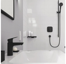 Badezimmer mit Badewanne, Armatur, Duschsystem, Ablage und Pflegeprodukten