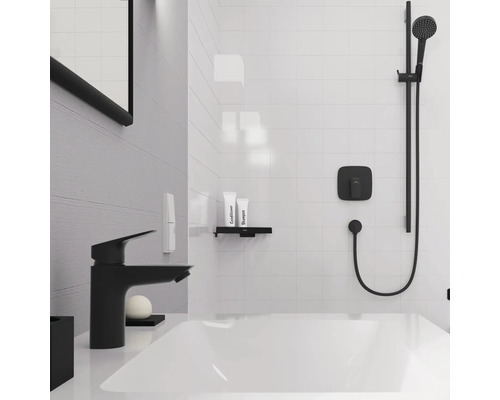 Badezimmer mit Badewanne, Armatur, Duschsystem, Ablage und Pflegeprodukten