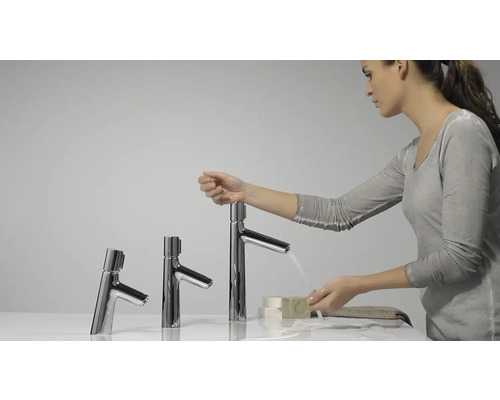 Frau wäscht sich an drei verschiedenen Chrom-Wasserhähnen die Hände mit Seife