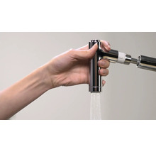 Hand hält eine glänzende Küchenarmatur, aus der Wasser fließt