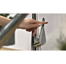 Eine Hand betätigt einen Wasserhahn aus Metall.