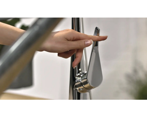 Eine Hand betätigt einen Wasserhahn aus Metall.