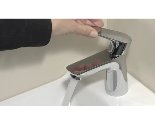 Hand betätigt Wasserhahn über Waschbecken