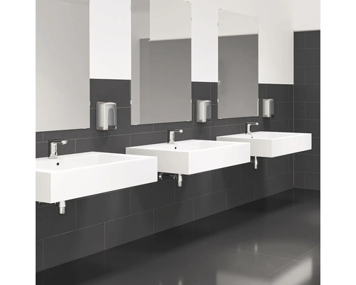 Drei Waschbecken mit Spiegeln und Seifenspendern in einem Badezimmer.