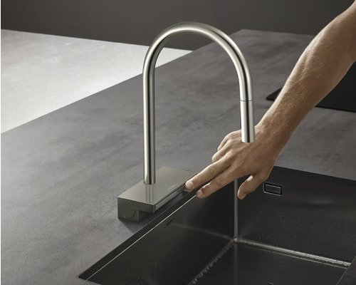 Küchenarmatur aus Metall mit hohem Auslauf neben einer Spüle, die von einer Hand bedient wird