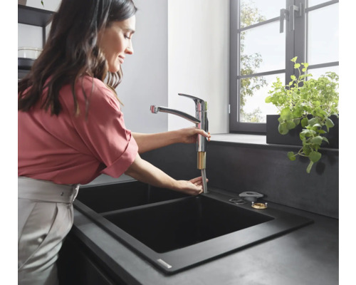 Frau installiert eine Küchenarmatur in ein Spülbecken.