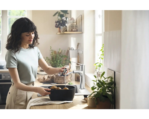 Frau wäscht Kartoffeln in einer Küche mit einer Armatur.