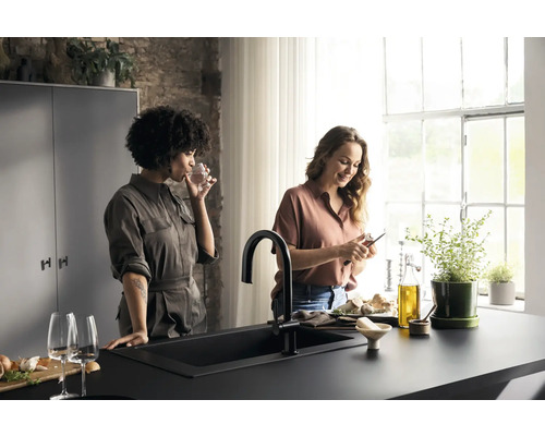 Helle Küche mit Spüle, Armatur und zwei Frauen beim Zubereiten von Speisen