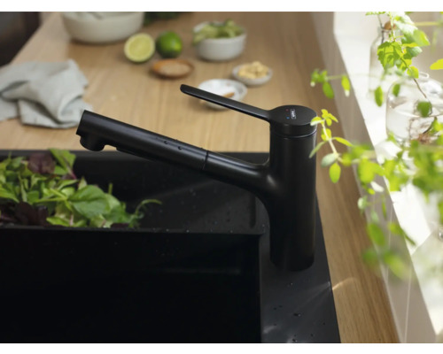 Schwarze Küchenarmatur neben einer Spüle mit Salat