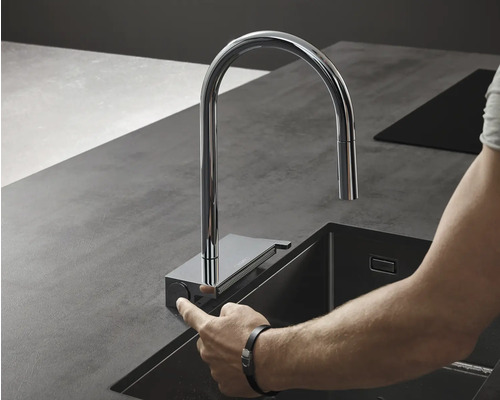 Küchenarmatur aus Chrom mit Bedienung per Knopfdruck neben einem Spülbecken