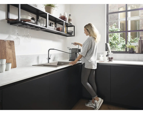 Moderne Küche mit Spüle, Armatur mit Ausziehbrause und einer Frau, die eine Kaffeemaschine bedient