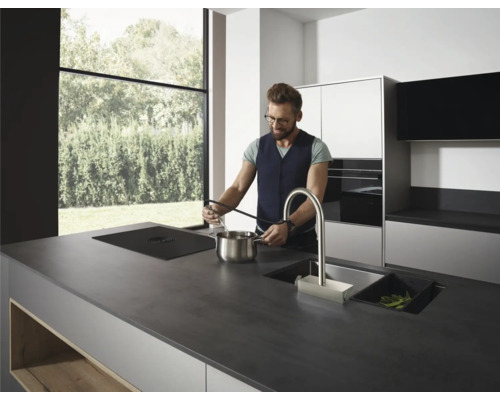 Moderne Küche mit Kochinsel, Spüle, Kochfeld und einer Person beim Kochen