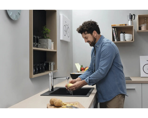 Mann wäscht Kartoffeln in einer modernen Küche mit Spüle und Armatur