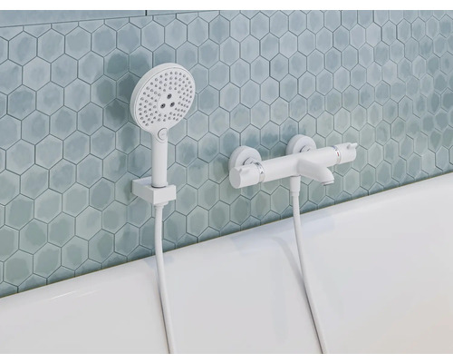 Aufnahme eines Badezimmers mit Badewanne, Armaturen und Handbrause vor sechseckigen Fliesen