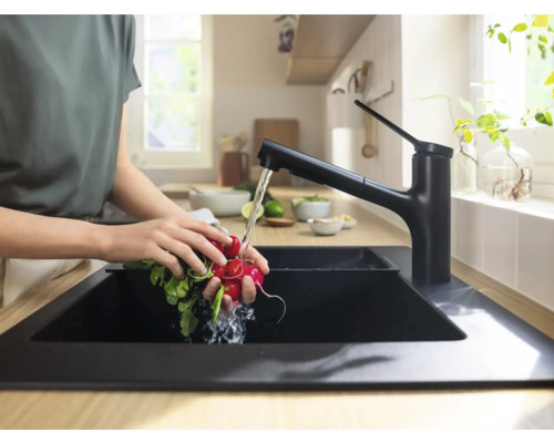 Frau wäscht Gemüse in einer Küchenspüle mit einer Armatur