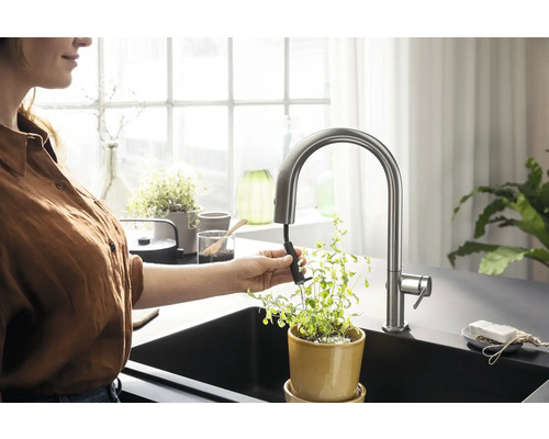 Frau gießt Pflanze am Spültisch mit ausziehbarer Küchenarmatur