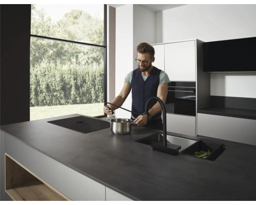 Moderne Küche mit Kochinsel, Spüle und Person beim Kochen