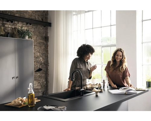 Helle Küche mit zwei Frauen an einer schwarzen Küchenarbeitsplatte mit Spüle und Armatur