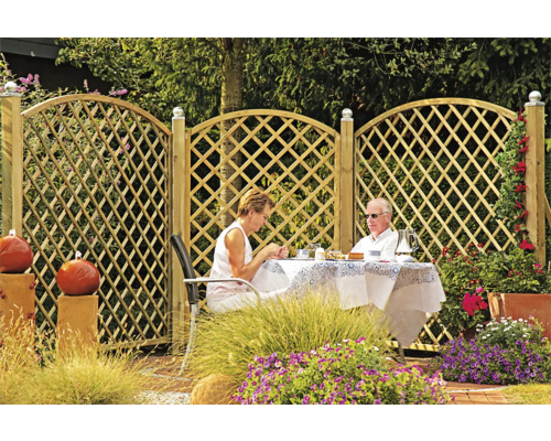 Holzzaun mit Rautenmuster im Garten mit sitzenden Personen