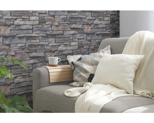 Wohnzimmer mit grauer Couch, Kissen, Decke und Steinwandtapete