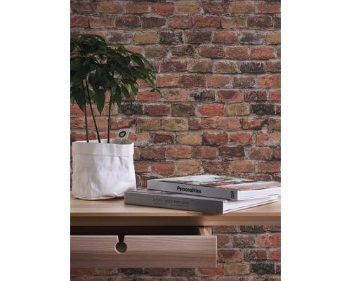 Tapete mit Backsteinmuster, Pflanze in Papiertüte, Bücher auf Tisch