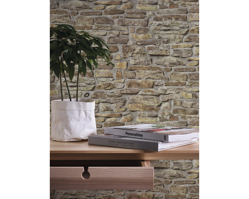 Wandgestaltung mit Steinoptik Tapete, Tisch, Zimmerpflanze und Büchern.