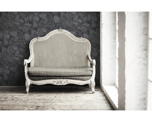 Antikes Sofa mit Holzrahmen und Polster vor einer Steinwand