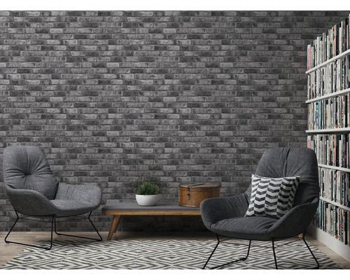 Wohnzimmer mit Backsteintapete, Sesseln und Bücherregal für ein gemütliches Ambiente.