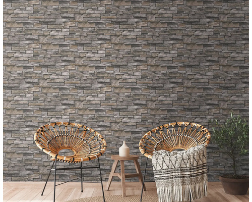 Zwei Korbsessel vor einer Wand mit Steinoptik-Tapete in einem hellen Raum.