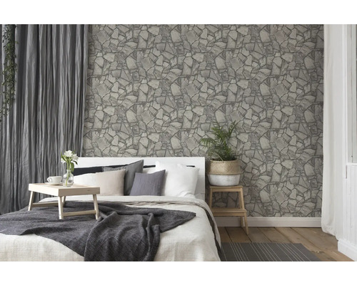 Schlafzimmer mit Bett vor einer Tapete mit Steinmuster.