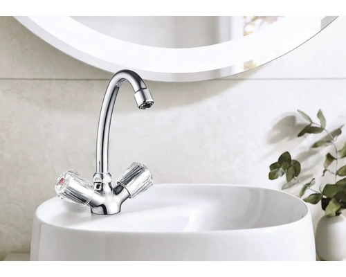 Glänzender Wasserhahn mit transparenten Griffen auf einem weißen Waschbecken