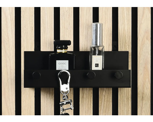 Schlüsselbrett mit Schlüsselanhänger und Parfümflaschen vor einer Holzpaneelwand