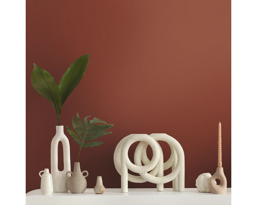 Dekorative Vasen und Kerzenständer auf einer weißen Oberfläche vor einer farbigen Wand