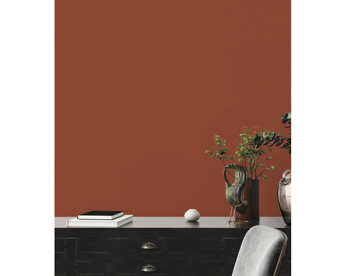 Dekorative Inneneinrichtung mit Kommode, Büchern, Vase und Zimmerpflanzen vor einer Wand